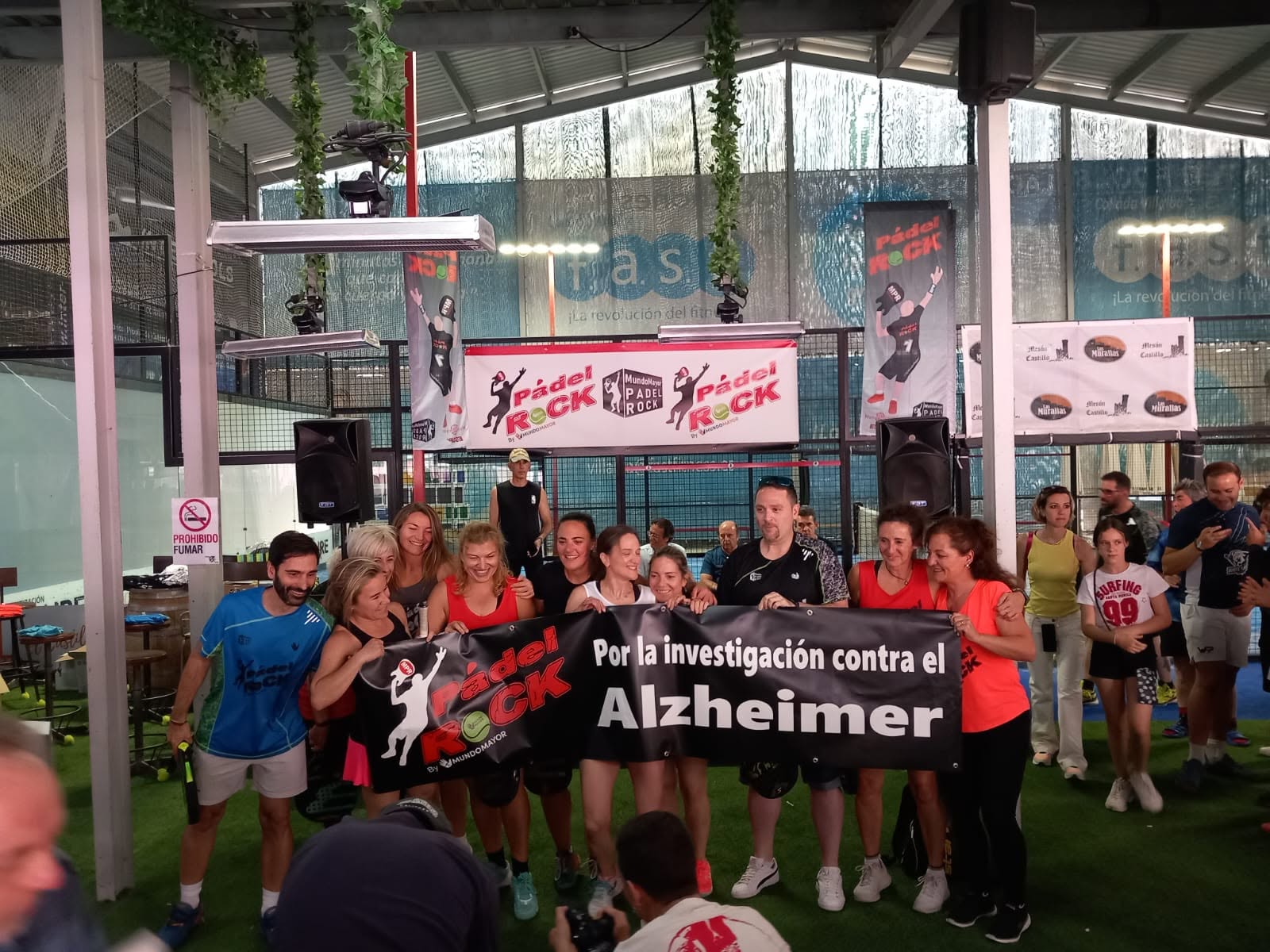 Participantes de Pádel Rock sostienen una pancarta por la investigación contra el Alzheimer
